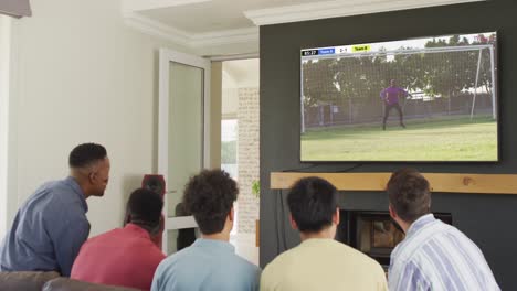 video of diverse friends sitting on sofa and watching football on television at home