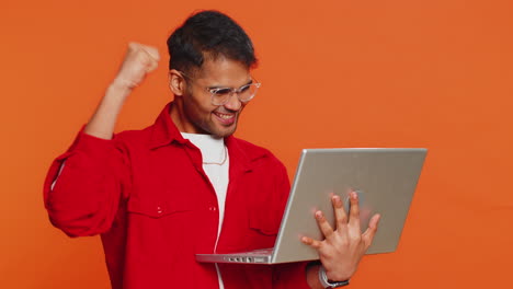 excited happy indian man working on laptop winning lottery game celebrating success victory