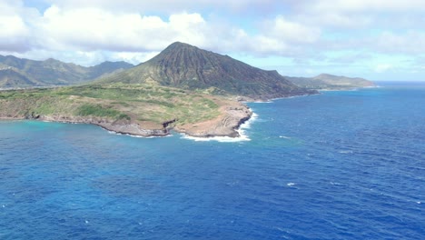 a drone shot of an ocean waves splash against rock on island