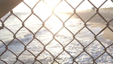 Puesta-De-Sol-En-La-Playa-A-Través-De-La-Cerca-De-Tela-Metálica