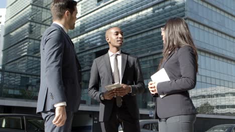 Coworkers-with-digital-devices-meeting-on-street