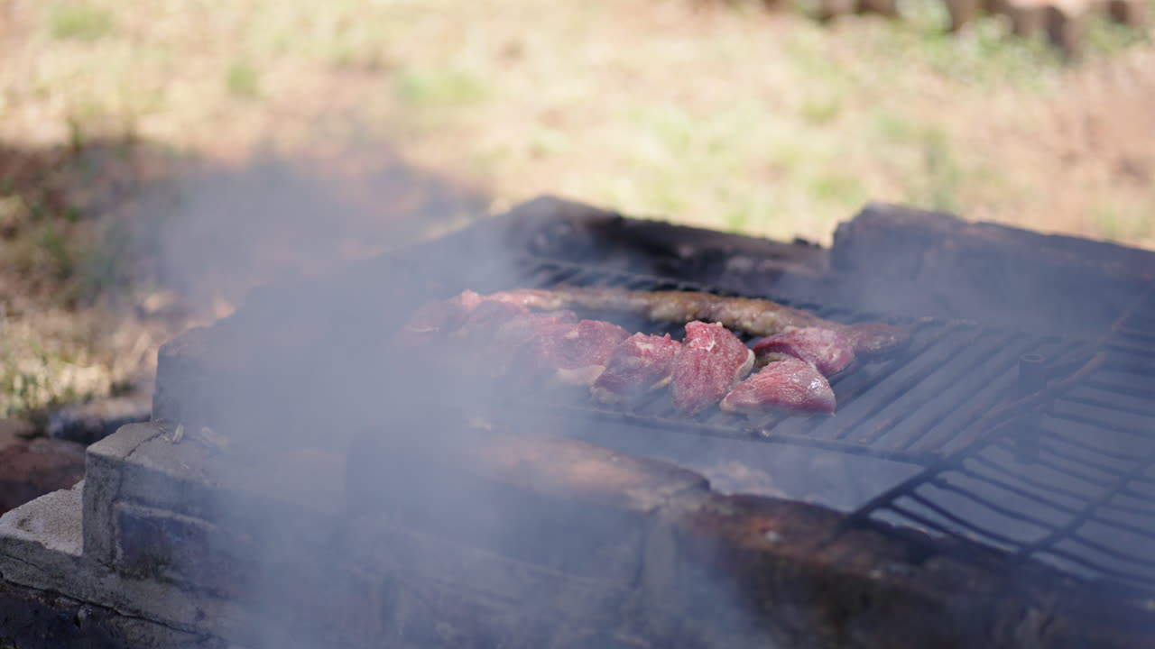 Grilling delicious Skirt steak and Top Sirloin Cap over open flame on an outdoor barbecue with smoke rising.