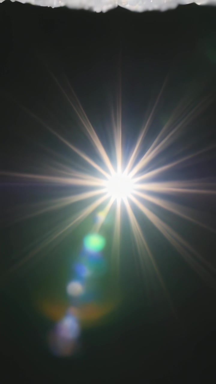Video verticale: Telecamera in movimento che crea una luce brillante che si trasforma in effetti a stella e bagliori colorati di notte.
