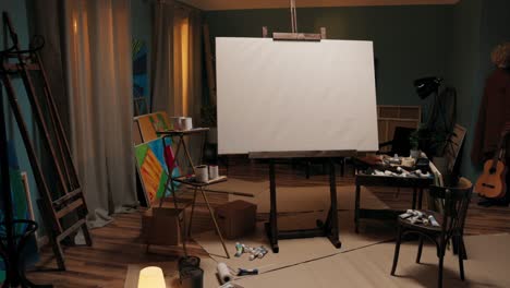 a workspace, a studio of a painter, an artist with a large easel with a canvas in the middle of the room. around the canvas scattered paints, brushes, cardboard boxes, a mess