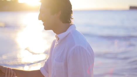 pareja besándose durante la puesta de sol en la playa y caminando hacia el mar después