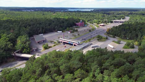 cars driving on a freeway interchange surrounded by forest leading to a lake on a cloudy day. unbelievable aerial view flight