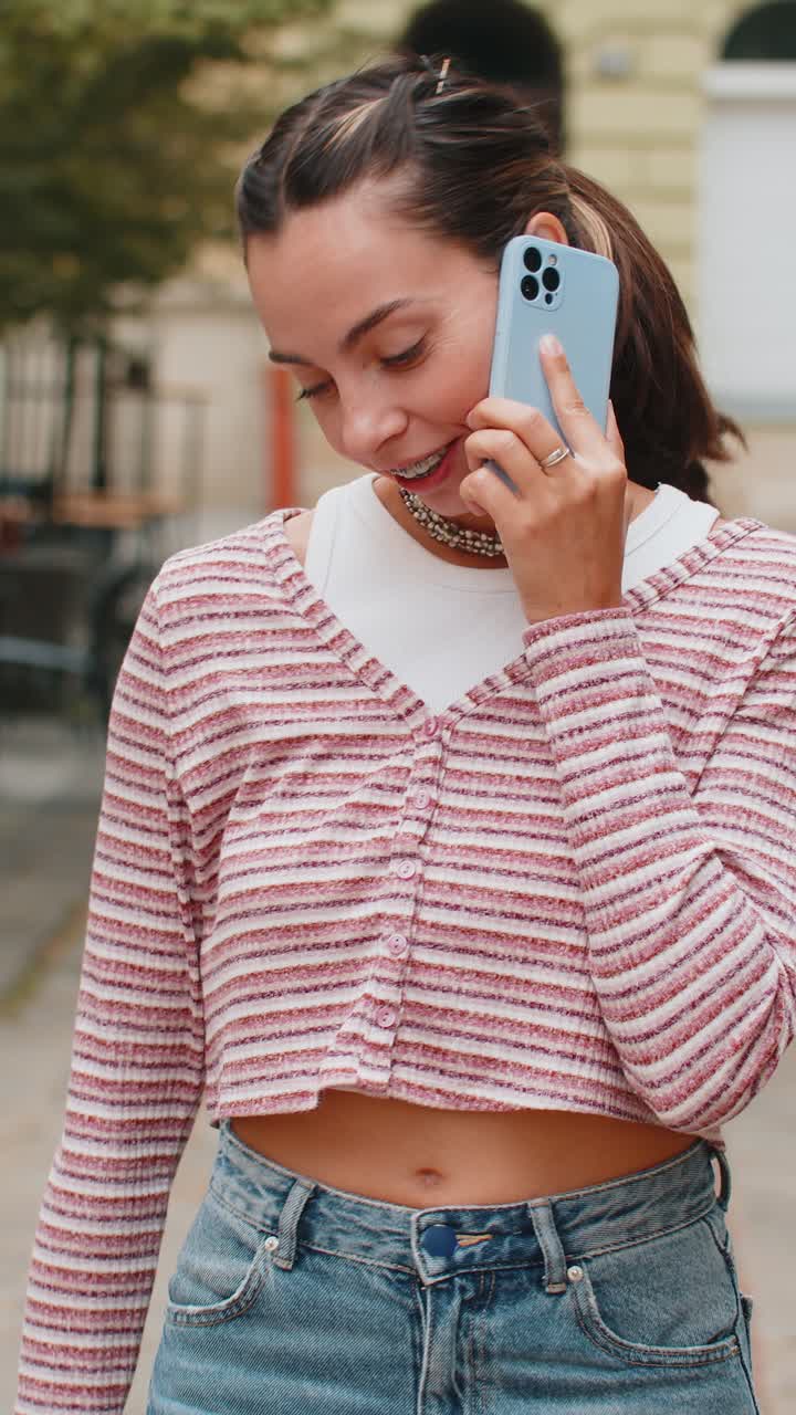 Donna felice in una piacevole conversazione sullo smartphone che si diverte a chiacchierare con gli amici in una strada della città