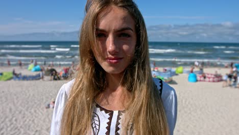 portrait of cute woman standing on the beach full of people. slow motion.