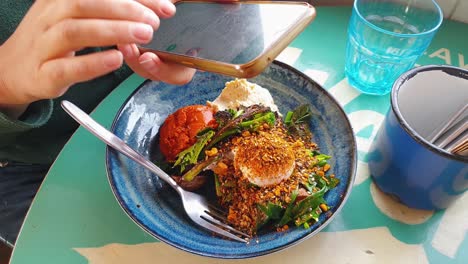 mujer enviando mensajes de texto y mensajes en el teléfono móvil durante un delicioso y saludable desayuno en un café local, cerca de una persona que usa el móvil