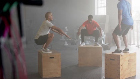 Diverse-group-fitness-class-jumping-onto-boxes,-cross-training-at-gym,-in-slow-motion