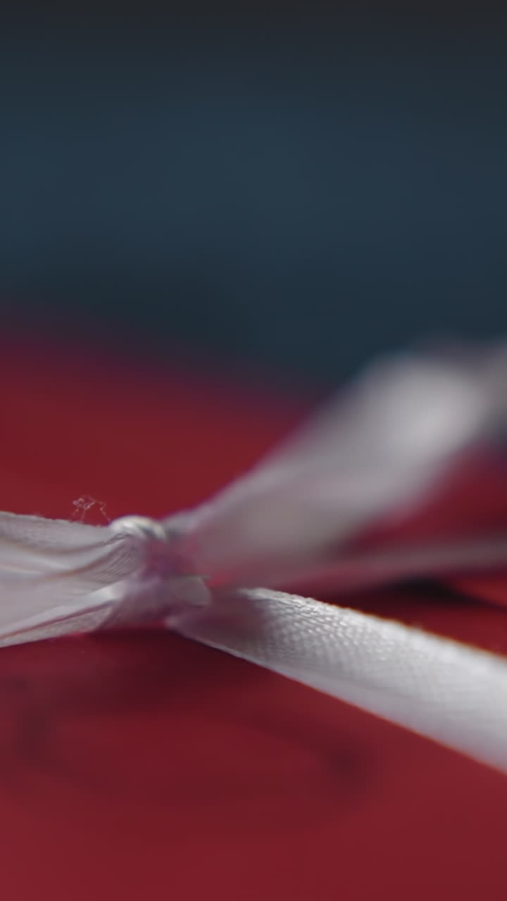 Red envelope with silk bow on dark background macro view. Holiday gift and invitation to party. Celebrate festive event and prepared present