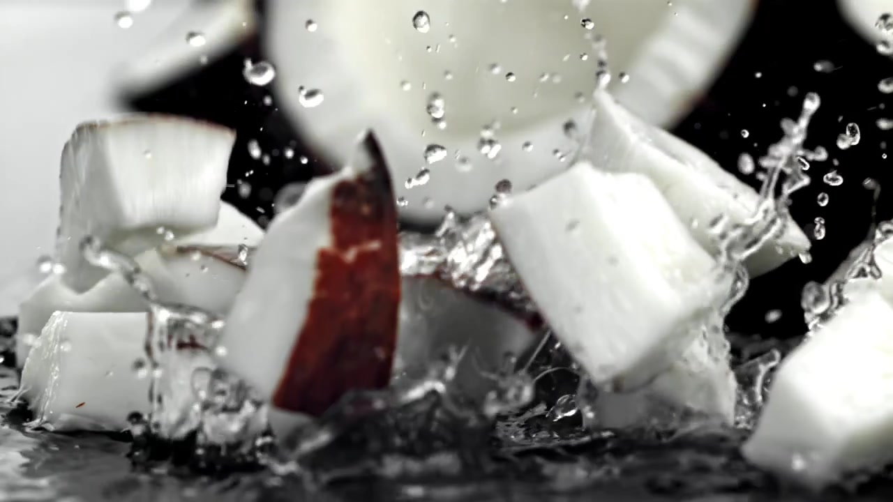 Movimento rallentato di pezzi di cocco fresco che cadono nell'acqua con schizzi