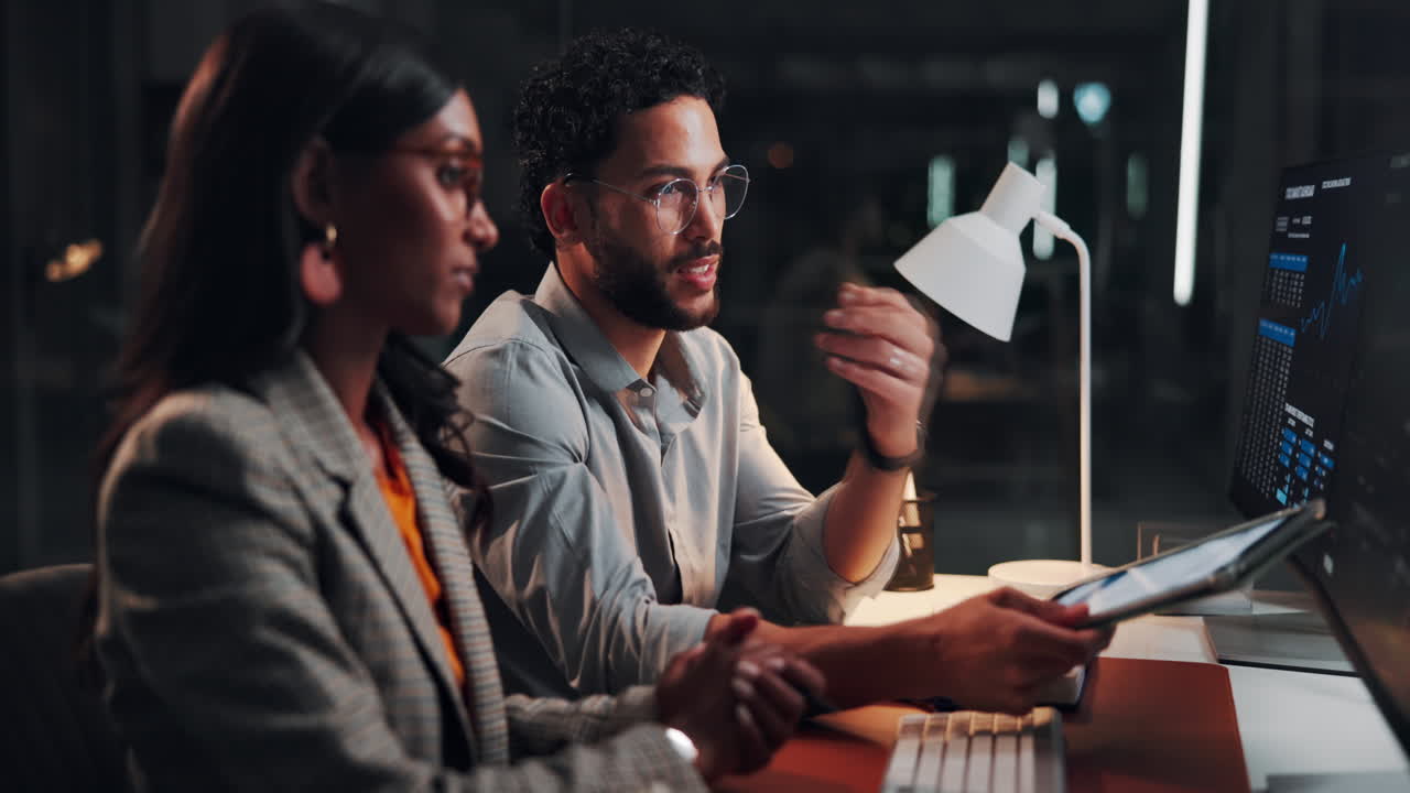 Two Business Professionals Collaborating and Analyzing Data in a Dark Office