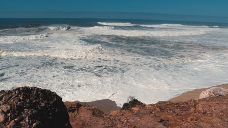 agua blanca de grandes olas rompiendo en praia do norte en nazaré en un día soleado