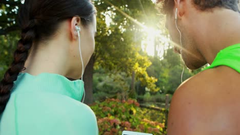 Couple-using-digital-tablet-while-listening-to-music-in-park