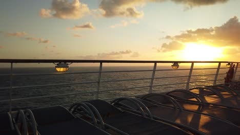 lounge chairs lined up along the railing of a cruise ship