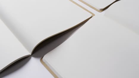 Close-up-of-open-blank-books-with-copy-space-on-white-background-in-slow-motion