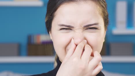 disgusted by the smell, young woman covers her nose.