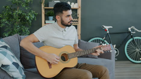 man playing acoustic guitar on a couch