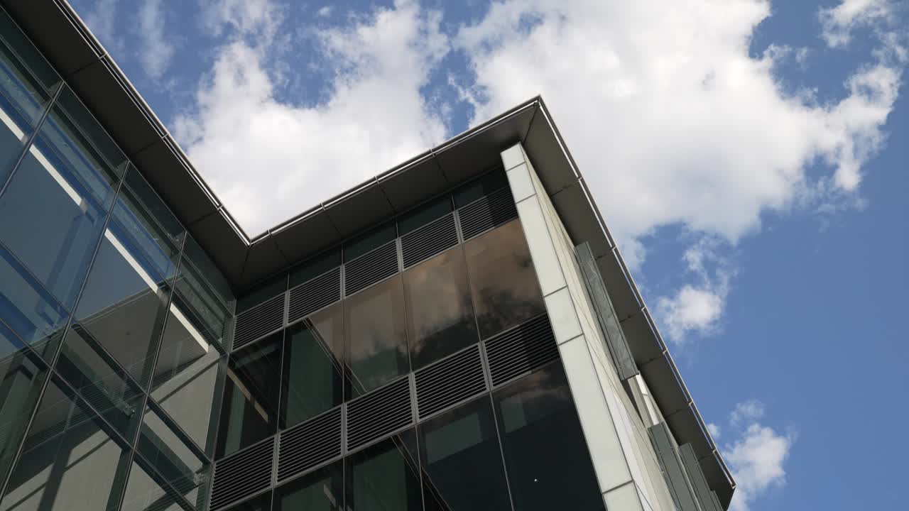 edificio de oficinas moderno con grandes ventanas de vidrio y vista del cielo azul y las nubes por encima en un día despejado