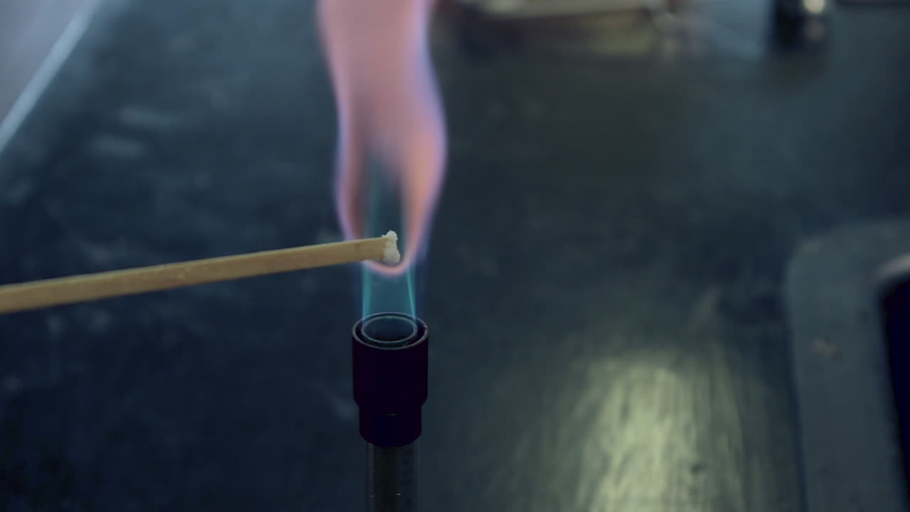 Close up of blue bunsen burner flame followed by potassium flame test burning lilac