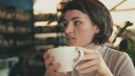 Portrait-Of-Young-Woman-Talking-To-Her-Friend-And-Having-A-Cup-Of-Coffee