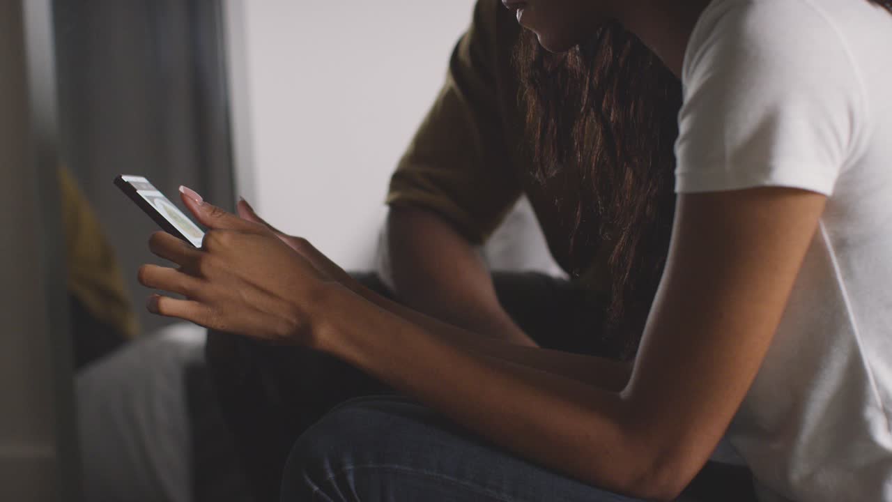 Close Up Of Young Couple Relaxing At Home At Night In Bedroom Looking At Mobile Phone Together 4