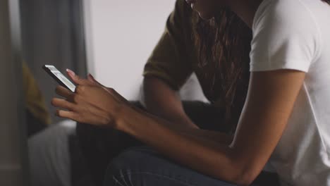 primer plano de una pareja joven relajándose en casa por la noche en el dormitorio mirando el teléfono móvil juntos 4