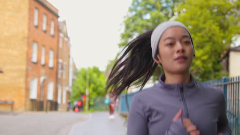 Close-Up-Of-Young-Woman-Exercising-Running-Along-Urban-Street-Wearing-Wireless-Earbuds-1