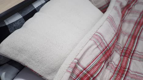 primer plano de una almohada blanca suave con una manta a cuadros roja y blanca