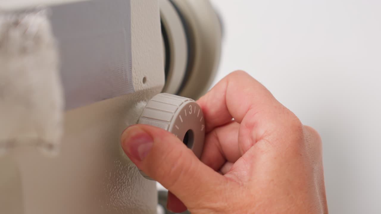 Hand adjusting stitch selection panel on sewing machine, ensuring perfect configuration, focusing on precise garment creation, controlling function, showcasing professional skill