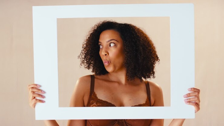 Studio Shot Of Confident Natural Woman In Underwear Making Funny Faces In Picture Frame