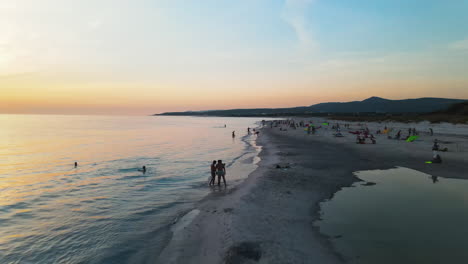 group of young people relaxing and enjoying vacation at the beaches of portovenere village in italy during evening with sea waves touching the coast