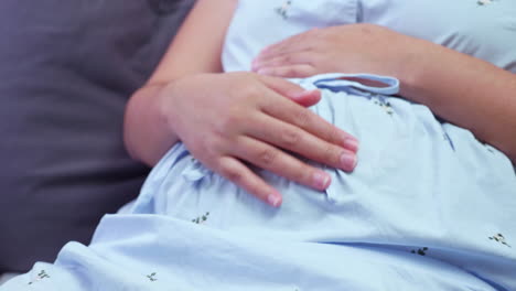 an expectant mother who is sitting on a couch is caressing her growing stomach