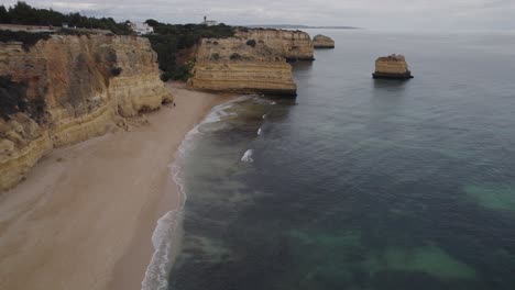 Aerial-view-across-jagged-Benagil-caves-in-Algarve-Portugal-with-scenic-transparent-ocean-coastline