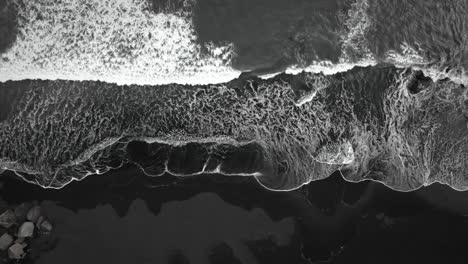 cinematic top down black sand beach aerial, waves crashing on volcanic sand, iceland