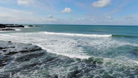 Aerial-coastal-shot-of-the-waves-crashing-in-the-sea-at-Spekes-Mill-beach-in-Devon