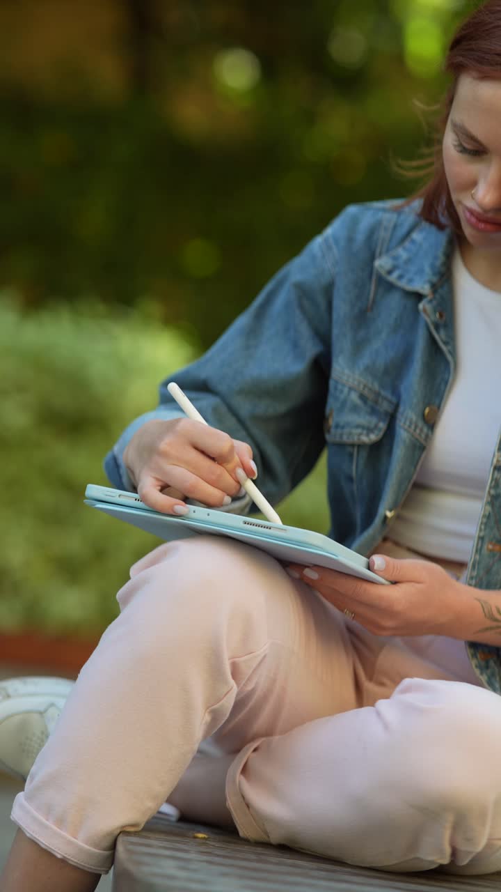 mujer dibujando en una tableta en un parque