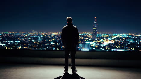 man contemplating cityscape at night