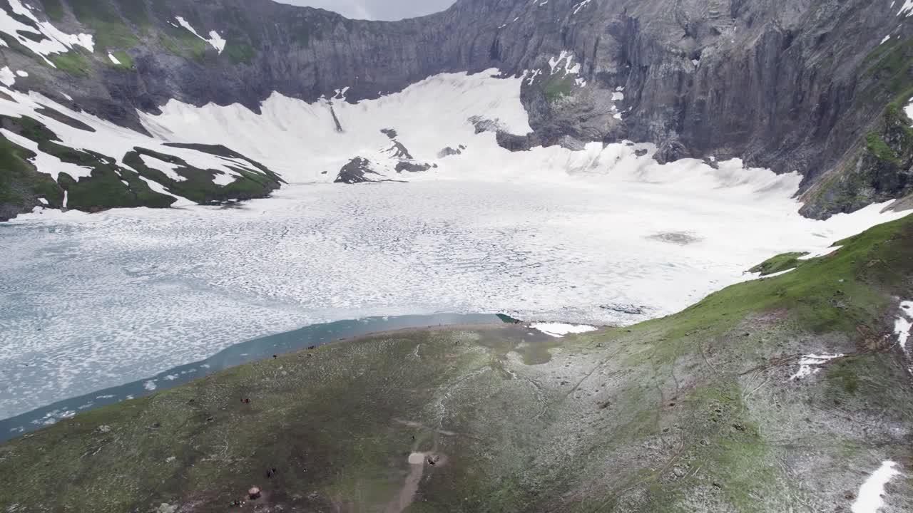 얼어붙은 래티 갈리 호수, 가파른 눈 인 절벽과 푸른 알파인 경사에 둘러싸인 넓은 풍경