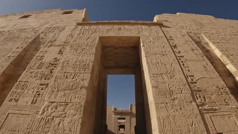 wide-angle view of the grand stone entrance to an ancient egyptian temple, adorned with detailed hieroglyphic carvings. the shot captures the symmetry and monumental scale of the historic structure.