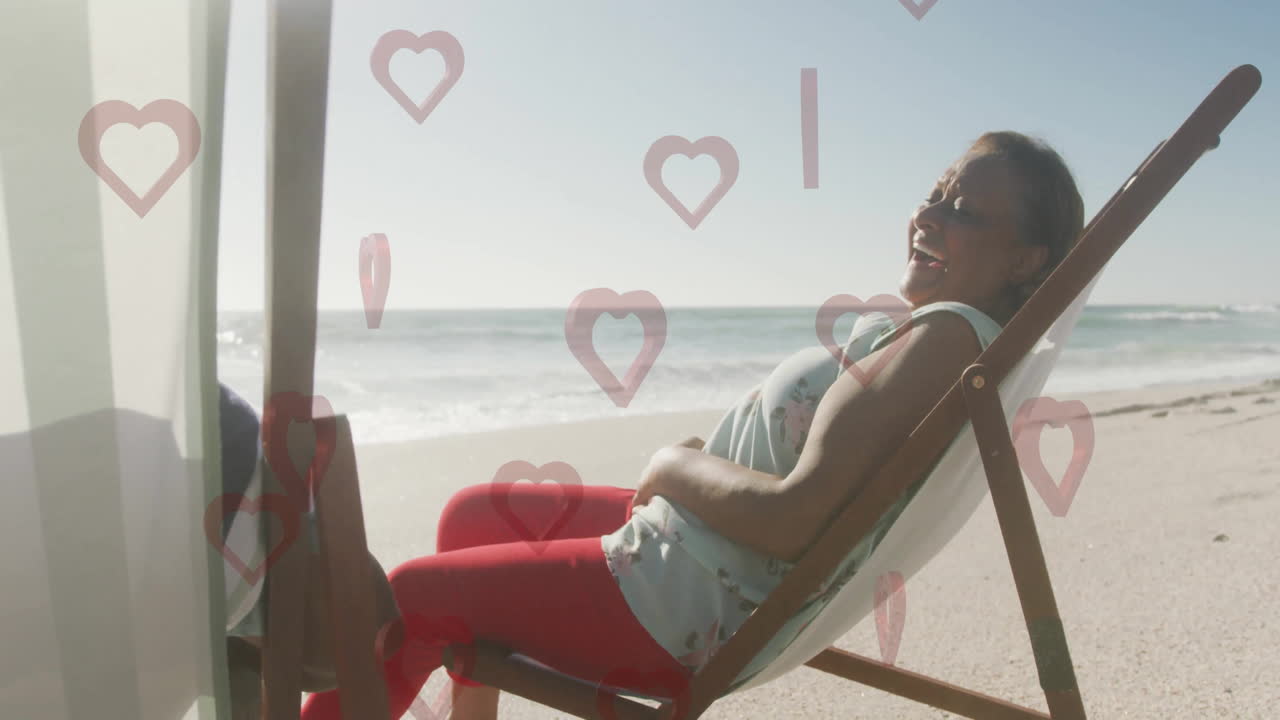 Relaxing on beach chair, woman enjoying animation of heart shapes floating