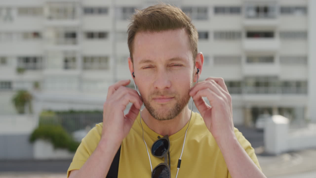 retrato joven guapo se pone auriculares escuchando música disfrutando de un viaje urbano relajado en una ciudad urbana soleada