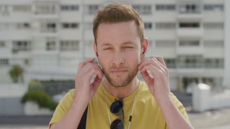 portrait-handsome-young-man-puts-on-earphones-listening-to-music-enjoying-relaxed-urban-commuting-in-sunny-urban-city