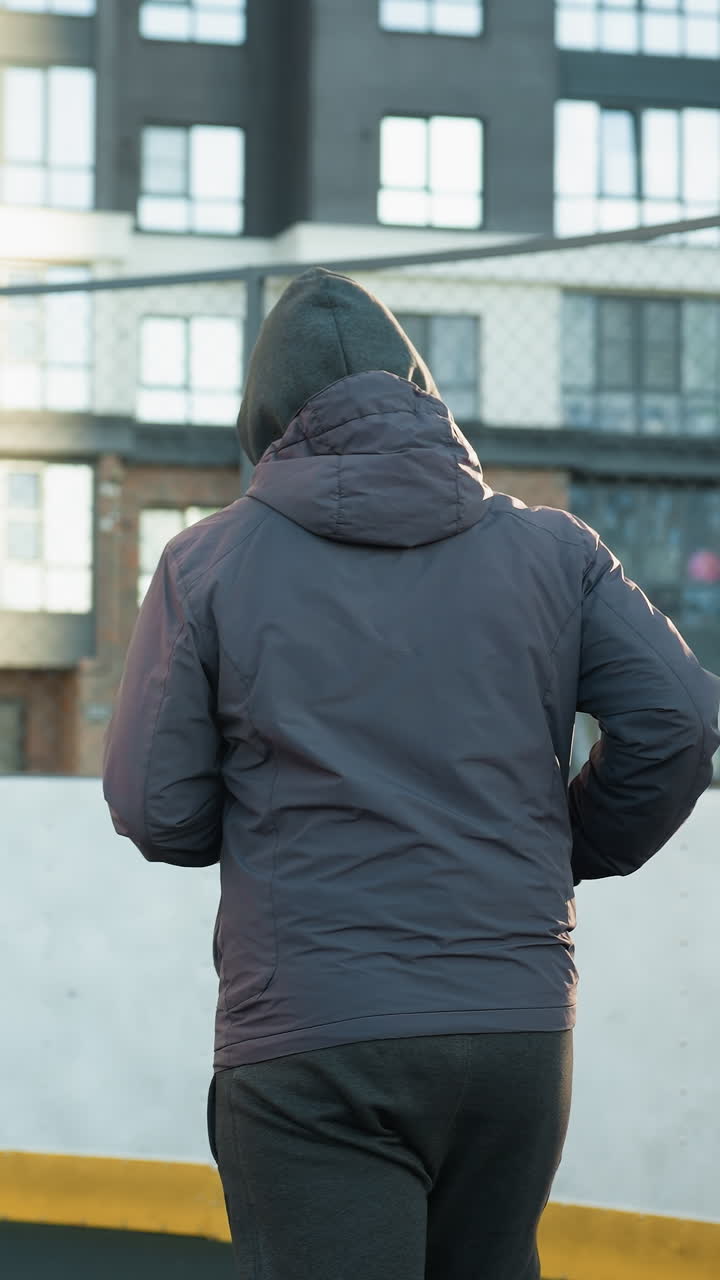 야외 스포츠 경기장에서 조하는 운동선수, 골포스트와 도시 고층 건물을 배경으로, 현대 도시 환경에서 활발한 생활 방식, 결단력 및 피트니스를 강조합니다.