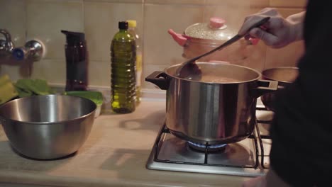 male cook stirring green pea and bean soup in kitchen - high angle, static shot