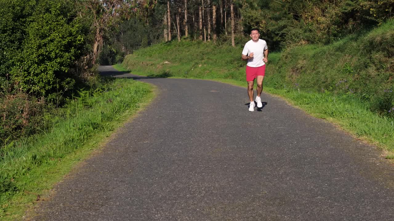 Active Man Running On Paved Country Road At Sunrise. Handheld Shot