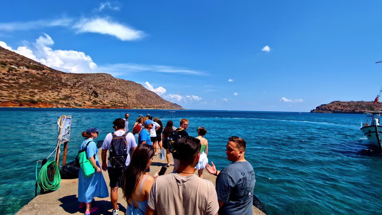 Tourists on a dock at Plaka, Crete, Greece waiting to be ferried to Spinalonga Island Fortress castles in the Elounda Gulf