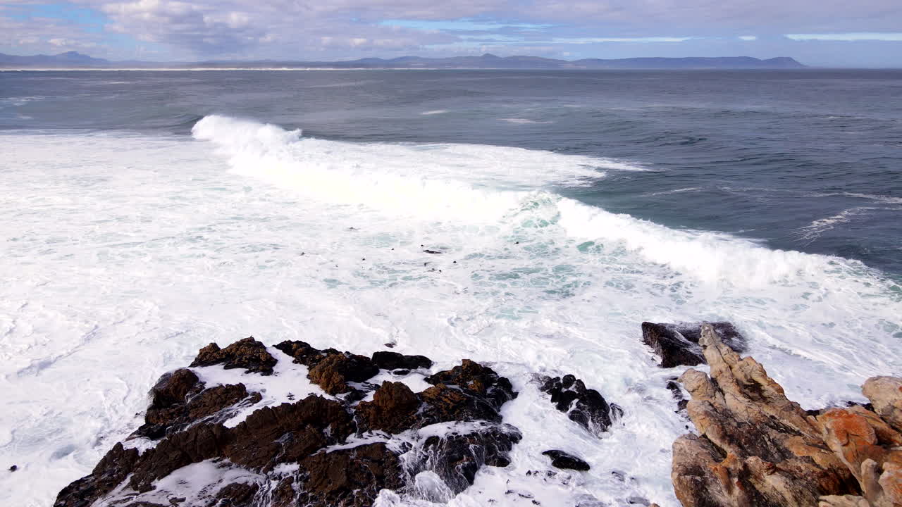 Big moody Atlantic waves crash into coastal rocks near shoreline, aerial dolly