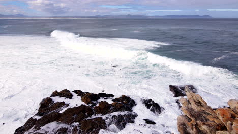 big moody atlantic waves crash into coastal rocks near shoreline, aerial dolly